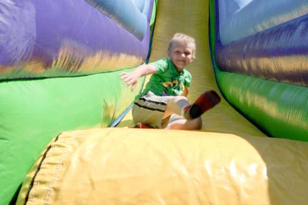 A child sliding down a bouncing castle slide.